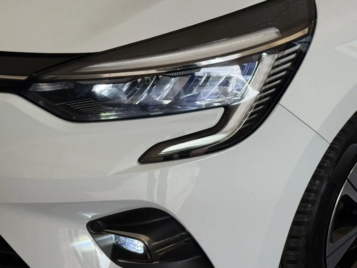 Gros plan sur le phare avant droit blanc de la Renault Clio Business TCe 100 GPL avec feu LED et partie de la roue visible.