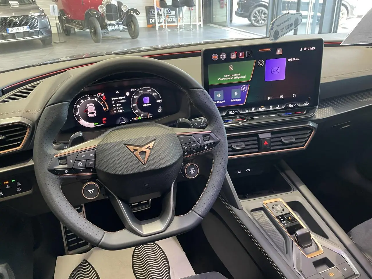 Vue intérieure du volant CUPRA avec logo cuivré et tableau de bord digital, écran tactile HD et finitions noires texturées.