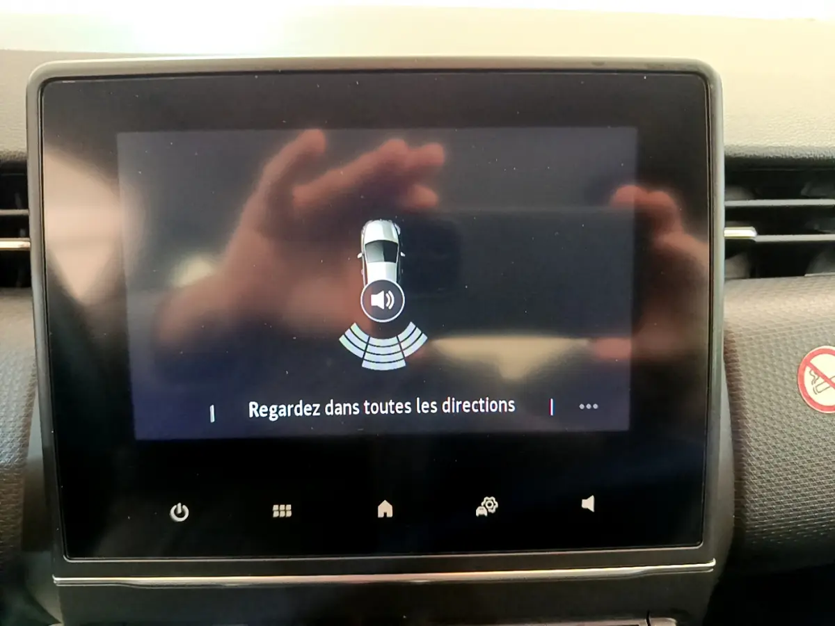 Écran tactile central de la Renault Clio Business blanc 2021 montrant l'alerte de capteurs de stationnement arrière.