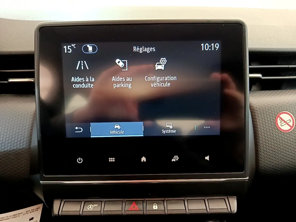 Écran tactile central de la Renault Clio Business blanc 2021 affichant les réglages d’aides à la conduite et parking.