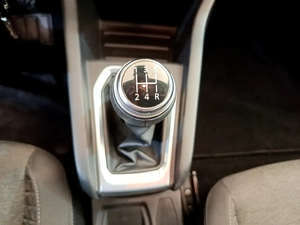 Le levier de vitesses manuel noir de la Renault Clio Business blanc, vu de dessus entre les sièges avant.