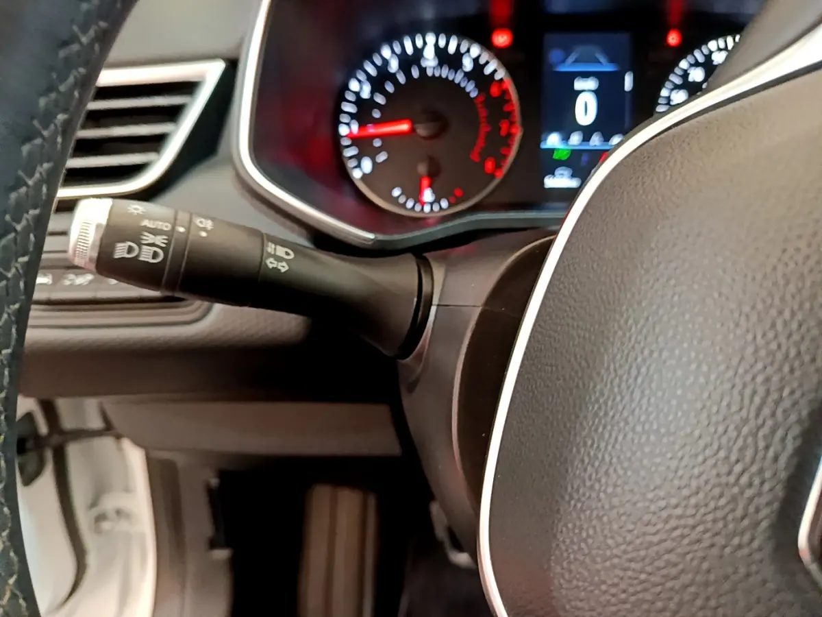 Gros plan sur le volant noir et le combiné d'instruments éclairé d'une Renault Clio Business blanche de 2021.