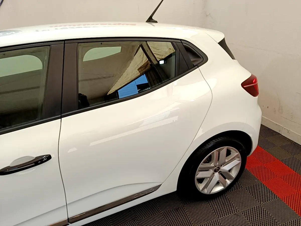 Vue côté droit arrière d'une Renault Clio Business blanche avec jante alliage et poignées noires.