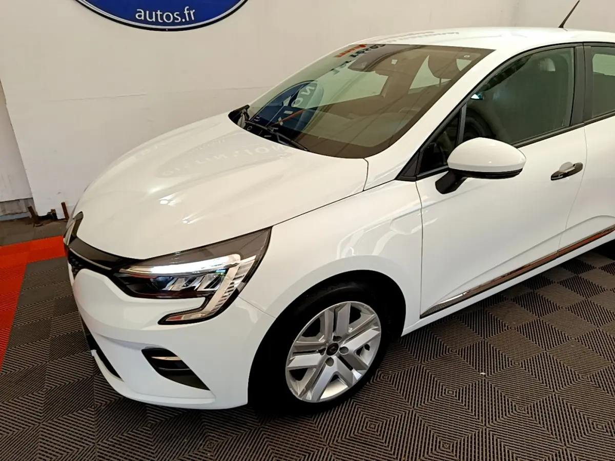 Renault Clio Business blanc vue 3/4 avant droit, phares LED et jantes alliage visibles sur sol damier.