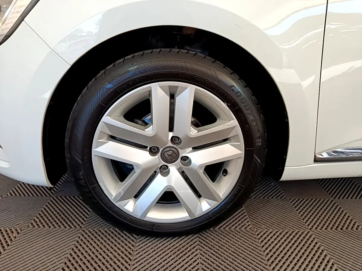 Vue rapprochée de la roue arrière côté gauche d'une Renault Clio Business blanche avec jante visible et carrosserie brillante.