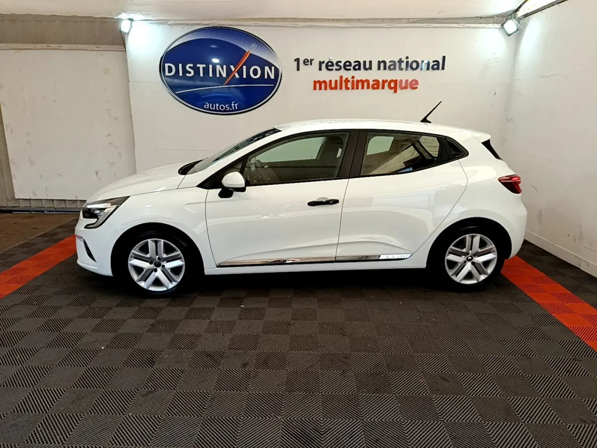 Profil côté gauche d'une Renault Clio Business blanche 2021 avec jantes alliage et poignées noires dans un showroom.