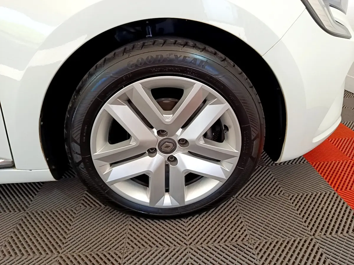 Gros plan sur la roue avant droite de la Renault Clio Business blanche, mettant en valeur la jante alliage et le pneu Goodyear.