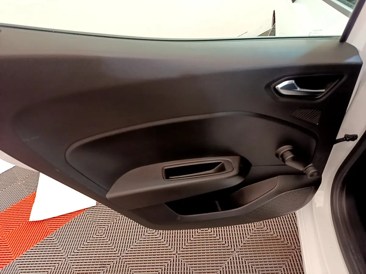 Vue intérieure de la porte avant droite noire d'une Renault Clio Business blanche, avec poignée et manivelle de vitre.