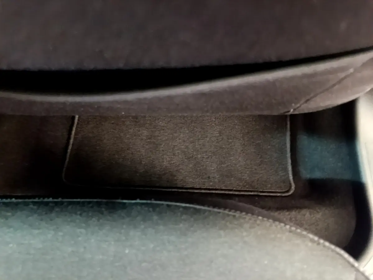 Gros plan sur le tapis de sol noir côté passager de la Renault Clio Business blanche, intérieur épuré.