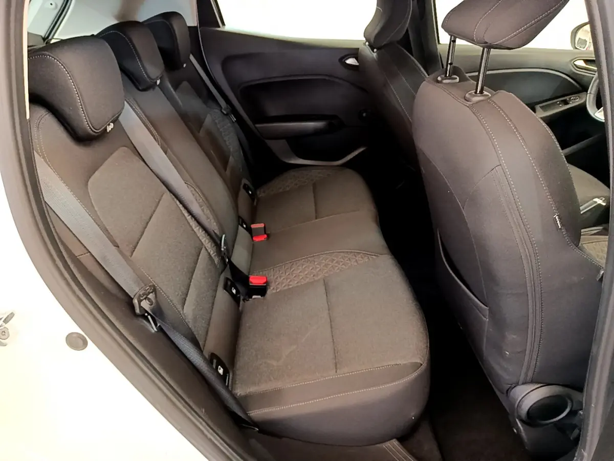 Vue intérieure côté gauche sur les sièges arrière noirs de la Renault Clio Business blanche, avec ceintures et appuie-têtes visibles.