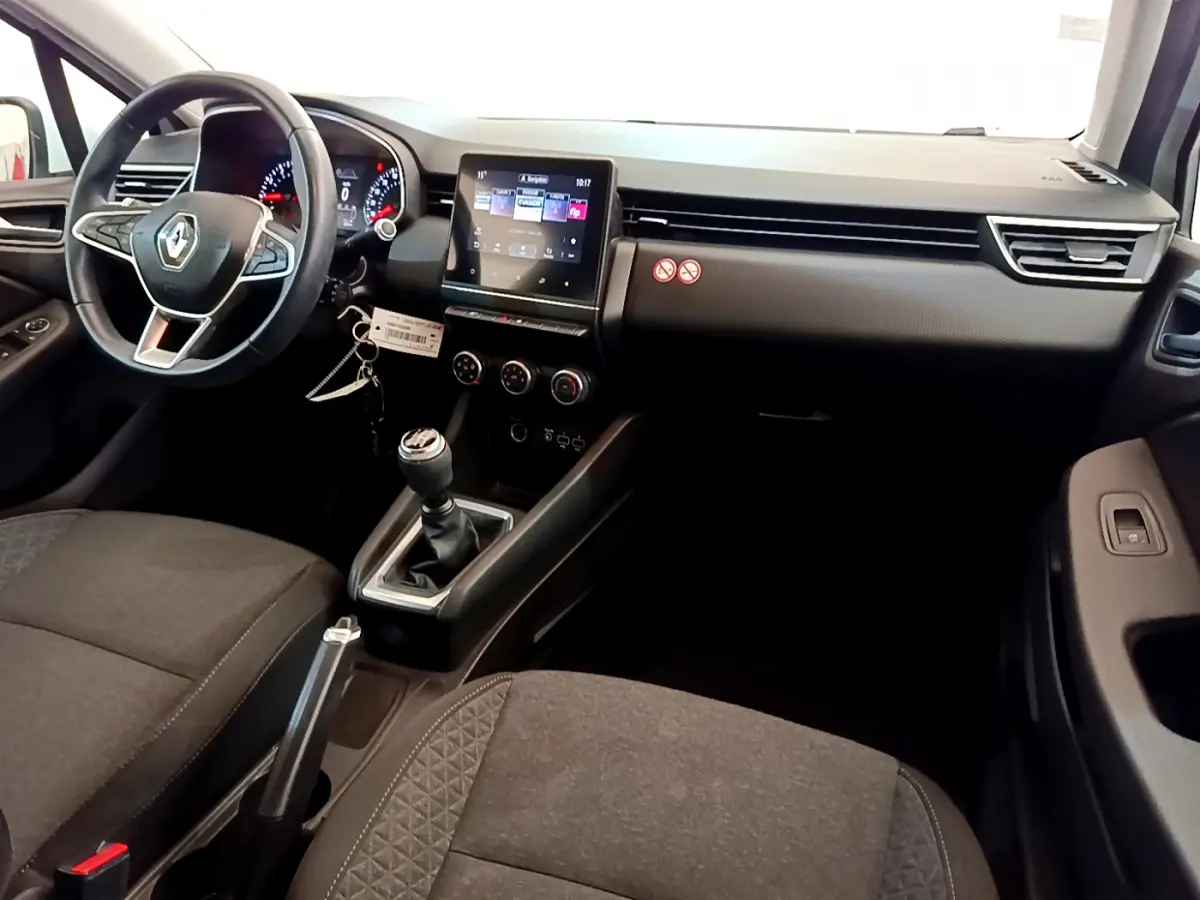 Vue intérieure avant droite de la Renault Clio Business blanche 2021 avec tableau de bord tactile et boîte manuelle.