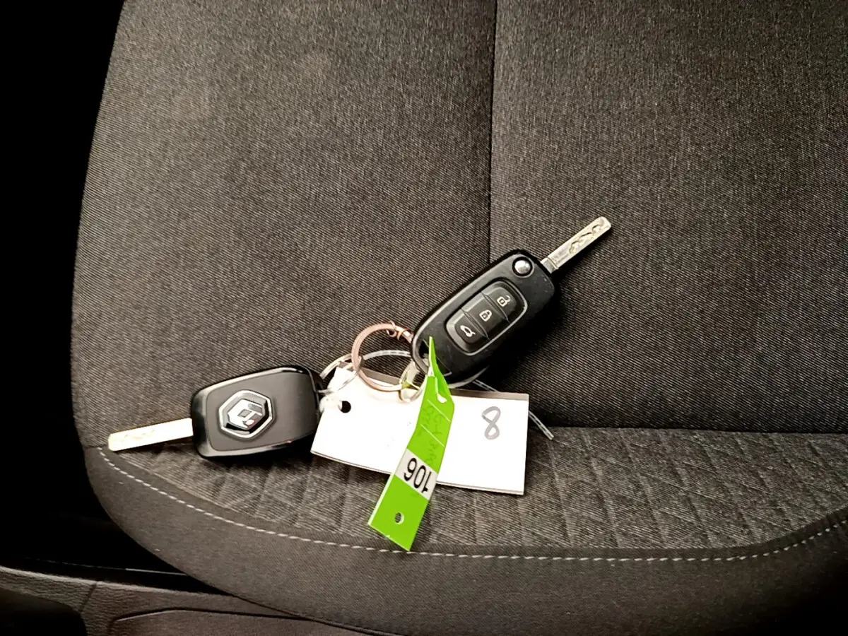 Gros plan sur les clés Renault posées sur un siège tissu gris foncé à motifs géométriques dans l'habitacle.