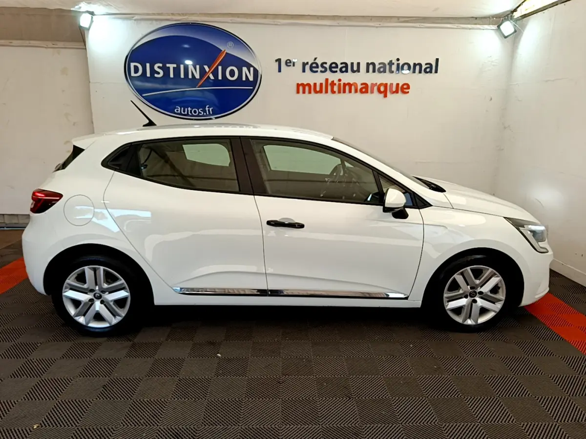 Profil côté gauche d'une Renault Clio Business blanche 2021, avec jantes alliage et poignées noires visibles en intérieur showroom.