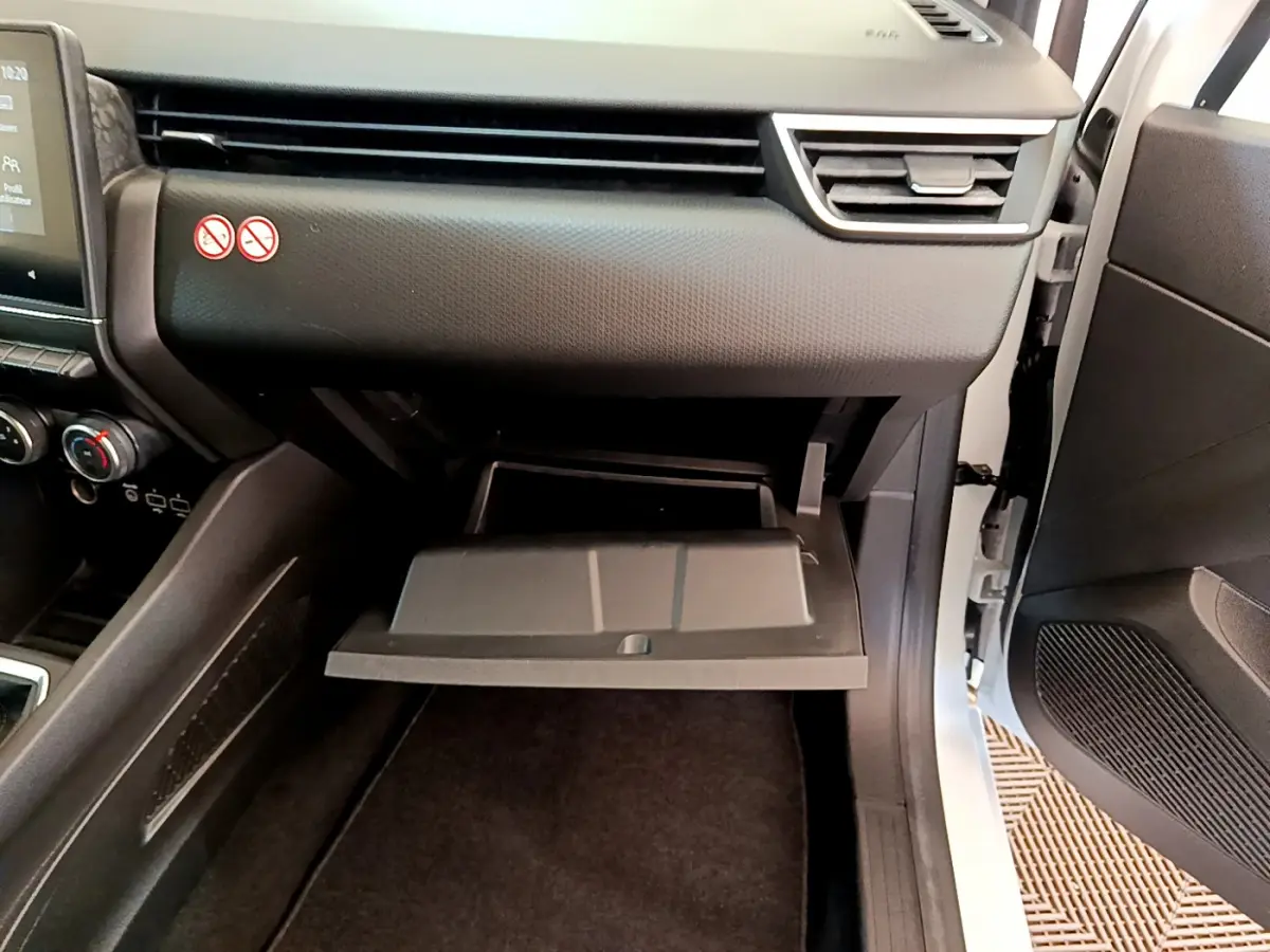 Vue intérieure côté passager de la Renault Clio Business blanche 2021, boîte ouverte du vide-poches et tableau de bord noir.