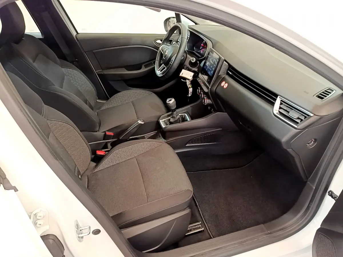 Intérieur côté droit d'une Renault Clio Business blanche, montrant sièges tissu, volant cuir et écran tactile central.
