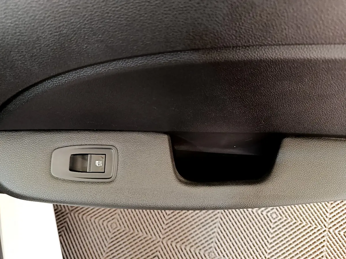 Gros plan sur la commande de verrouillage centralisé noire dans l'intérieur de la Renault Clio Business blanche.