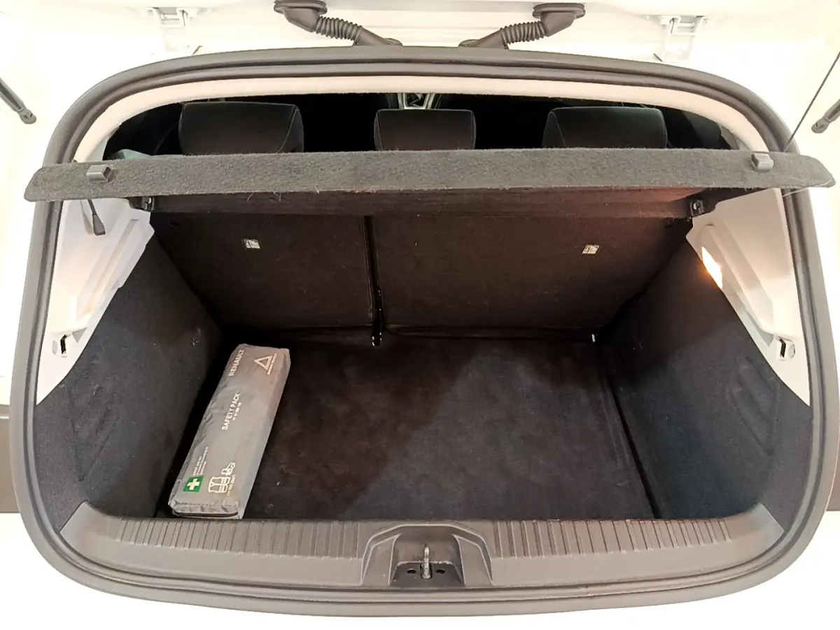 Coffre ouvert vu de l'arrière d'une Renault Clio Business blanche, avec cache-bagages et trousse de secours noire.