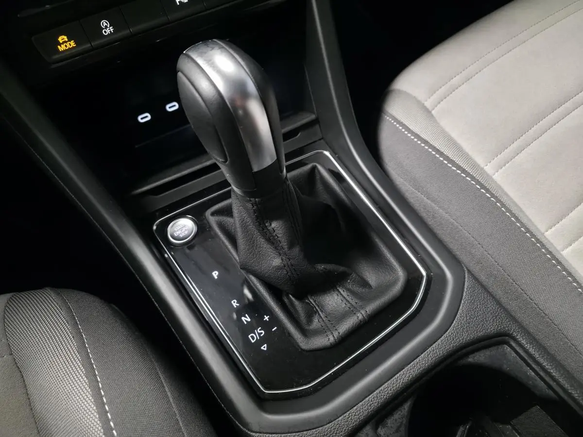 Le levier de vitesse automatique noir et argent du Volkswagen Touran 2024, avec siège gris clair adjacent.