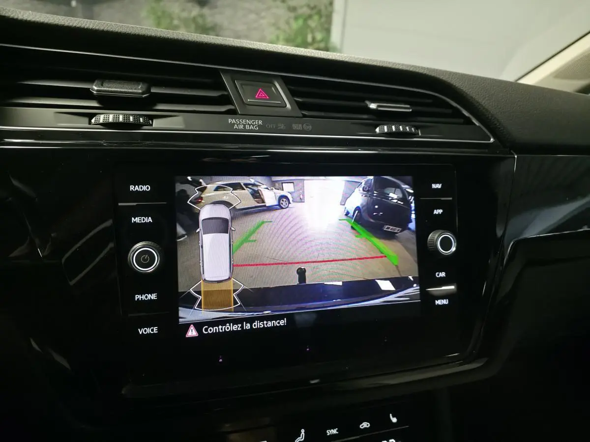 Écran tactile intérieur montrant la caméra de recul avec guidage vert et rouge du Volkswagen Touran bleu 2024.