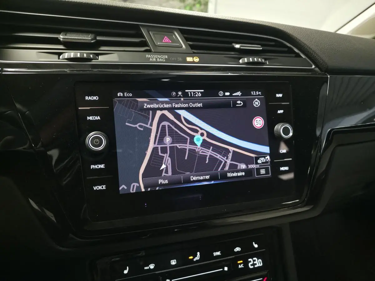 Écran tactile central du Volkswagen Touran 2024 affichant la navigation, entouré de commandes multimédia et climatisation.