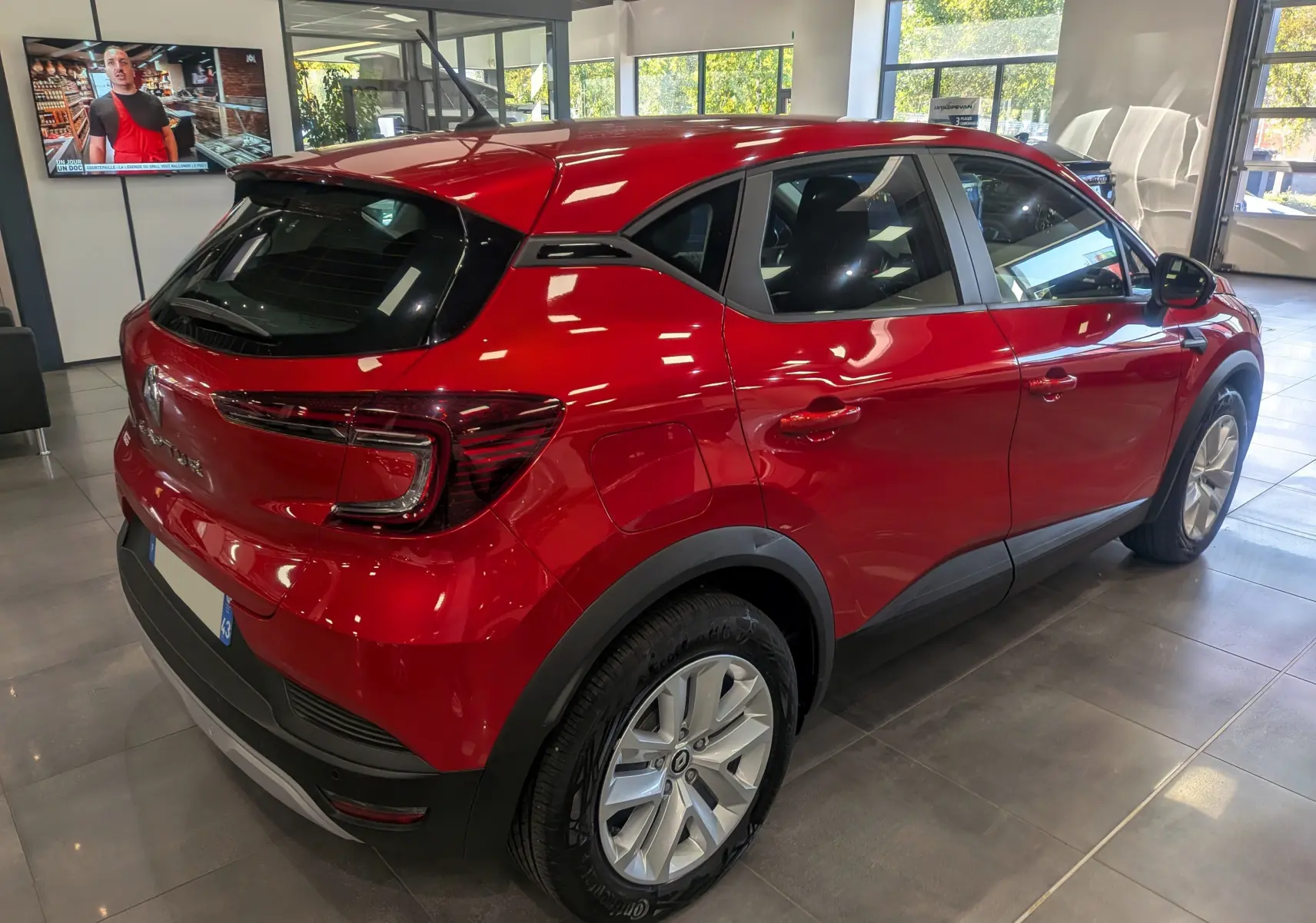 Renault Captur TCe 90 Zen rouge flamme vu en 3/4 arrière droit dans un showroom lumineux.