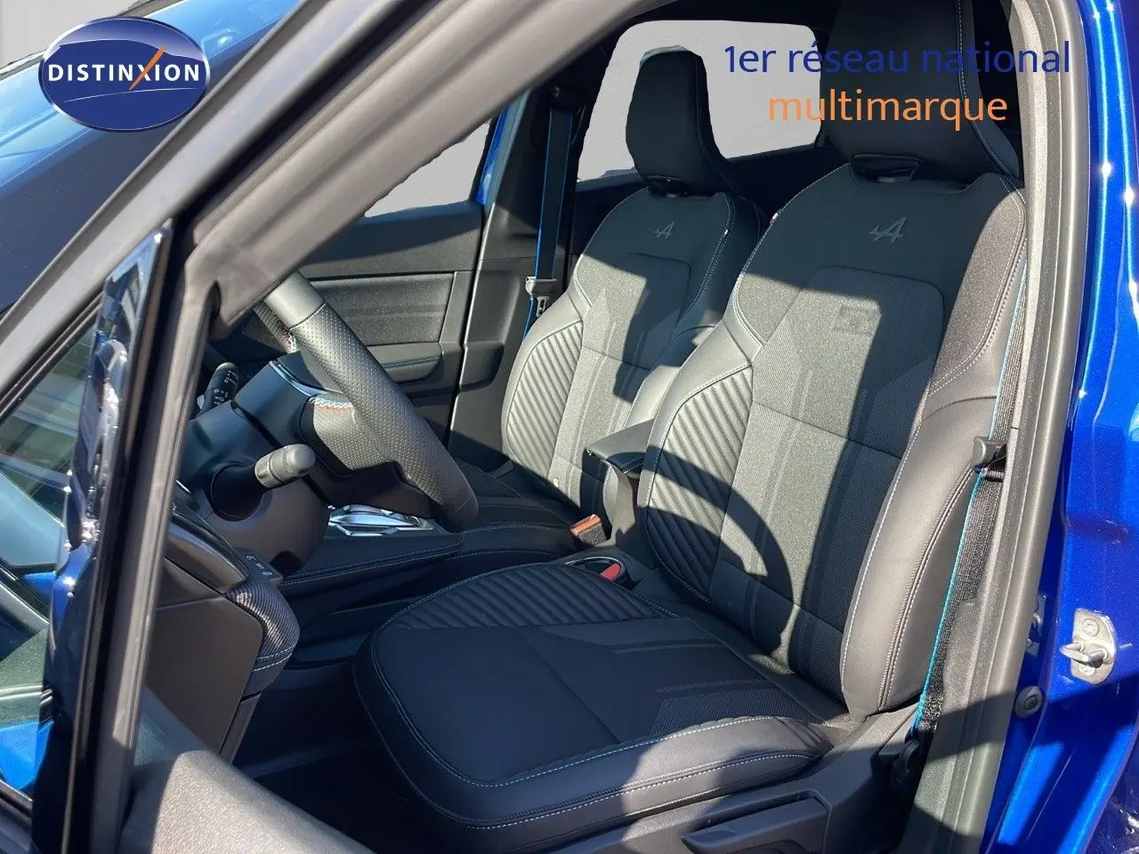 Intérieur côté conducteur du Renault Captur E-Tech hybride 2025, sièges noirs avec surpiqûres bleues et logo Alpine.