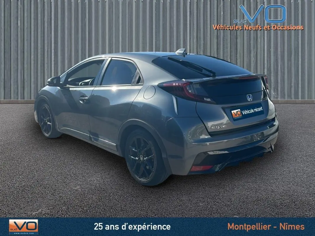 Vue 3/4 arrière droite d'une Honda Civic gris métallisé avec vitres surteintées et jantes alliage noires.