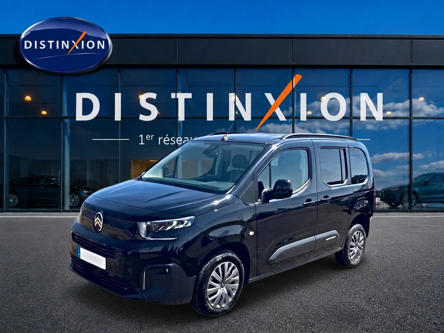 Citroën Berlingo noir vue 3/4 avant droit, avec barres de toit et jantes alu devant showroom Distinxion.