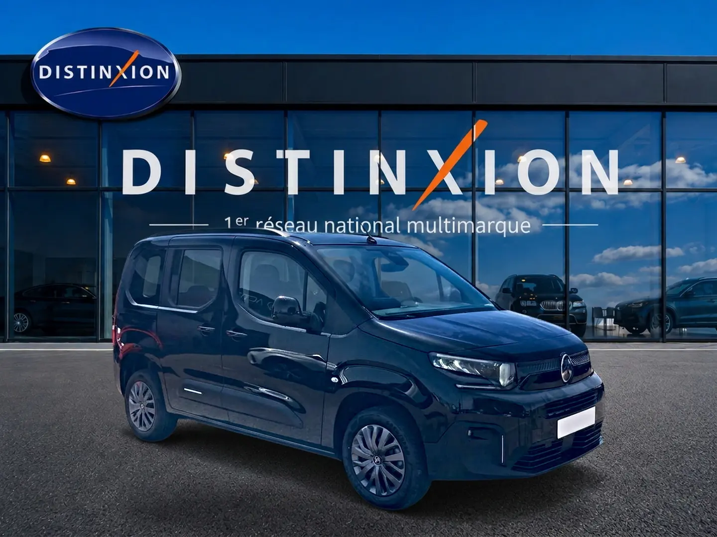 Vue 3/4 avant droit d'un Citroën Berlingo noir avec jantes acier et vitres teintées, devant une vitrine Distinxion.