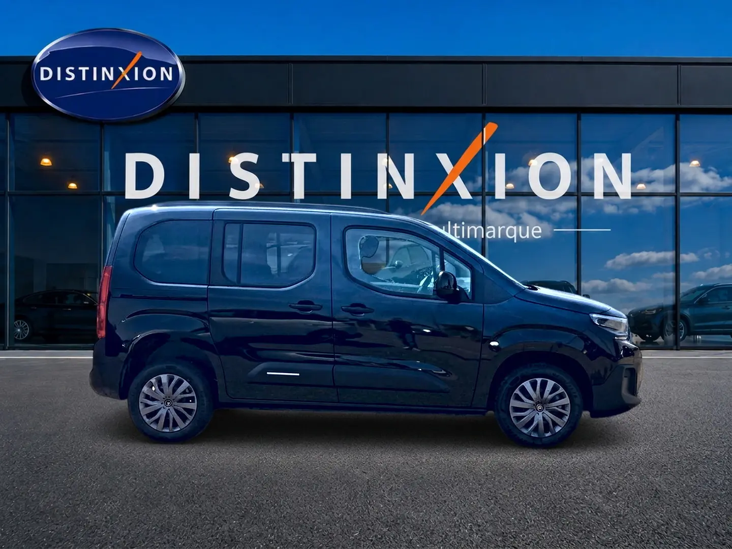 Profil droit d'un Citroën Berlingo noir 2026 garé devant une vitrine avec logo Distinxion.
