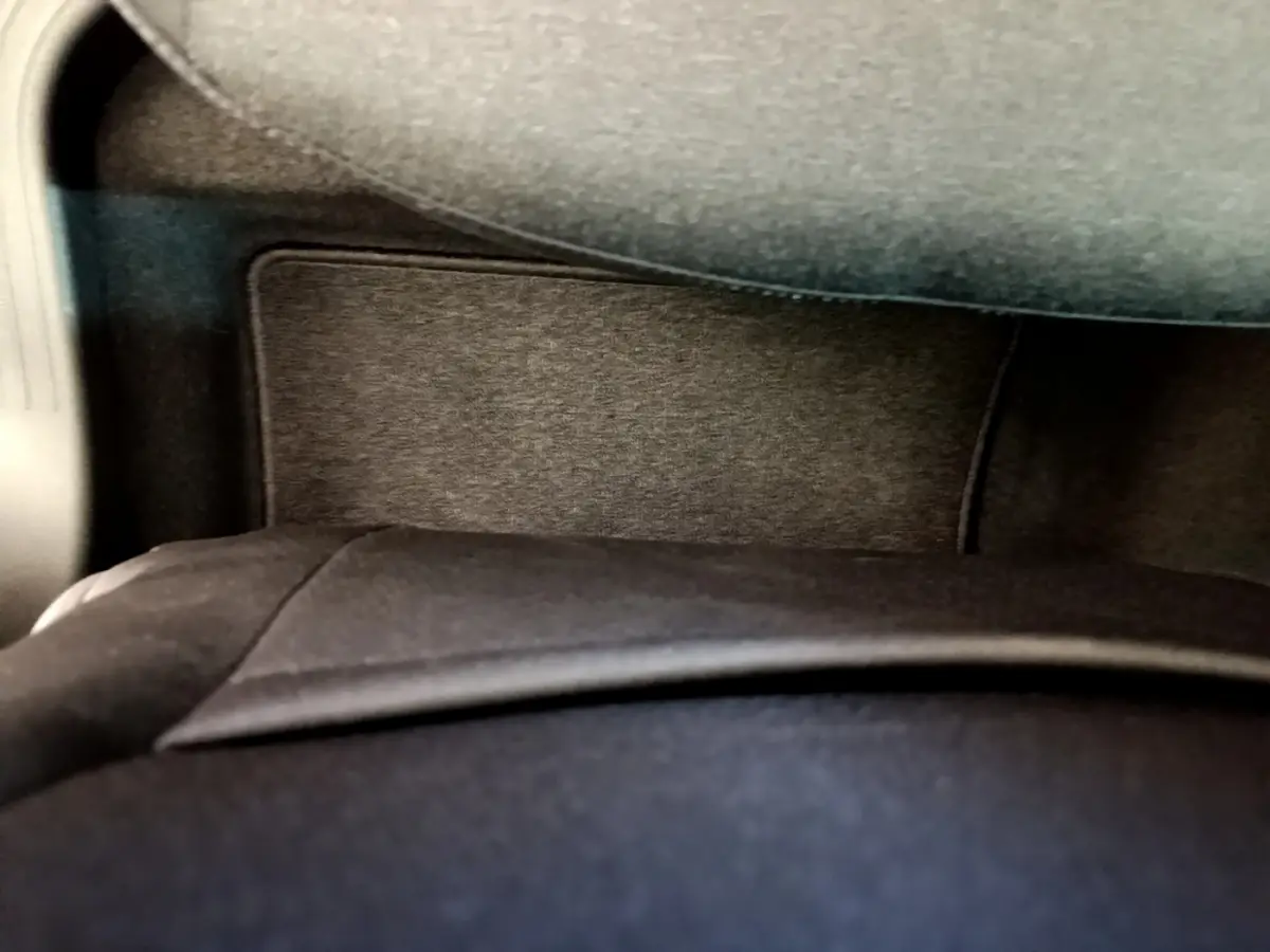 Détail de l'intérieur noir du coffre de la Renault Clio Business blanche, vue rapprochée sous tablette arrière.