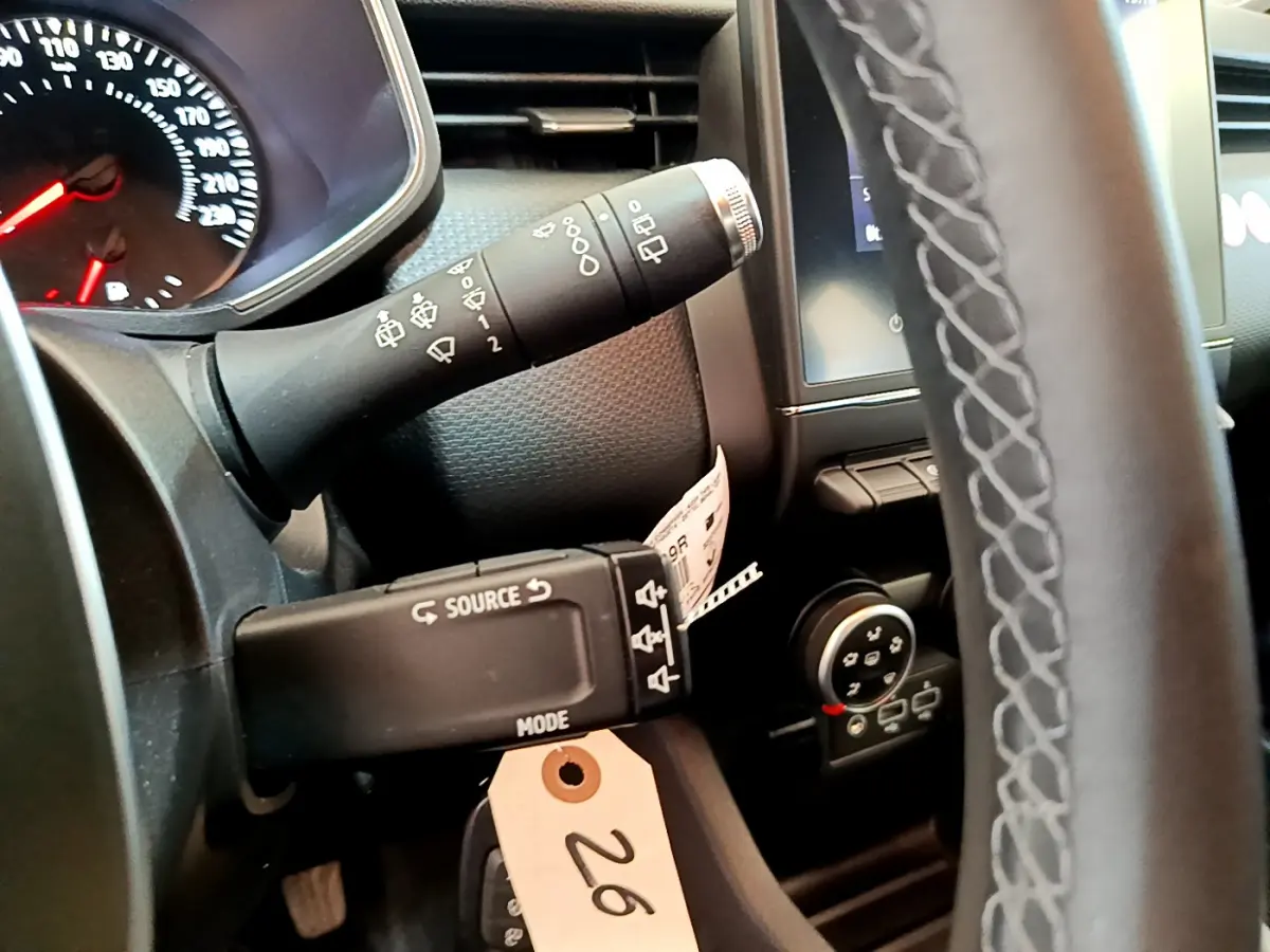 Gros plan sur le volant et commandes au volant d'une Renault Clio Business blanche, tableau de bord et écran tactile visibles.