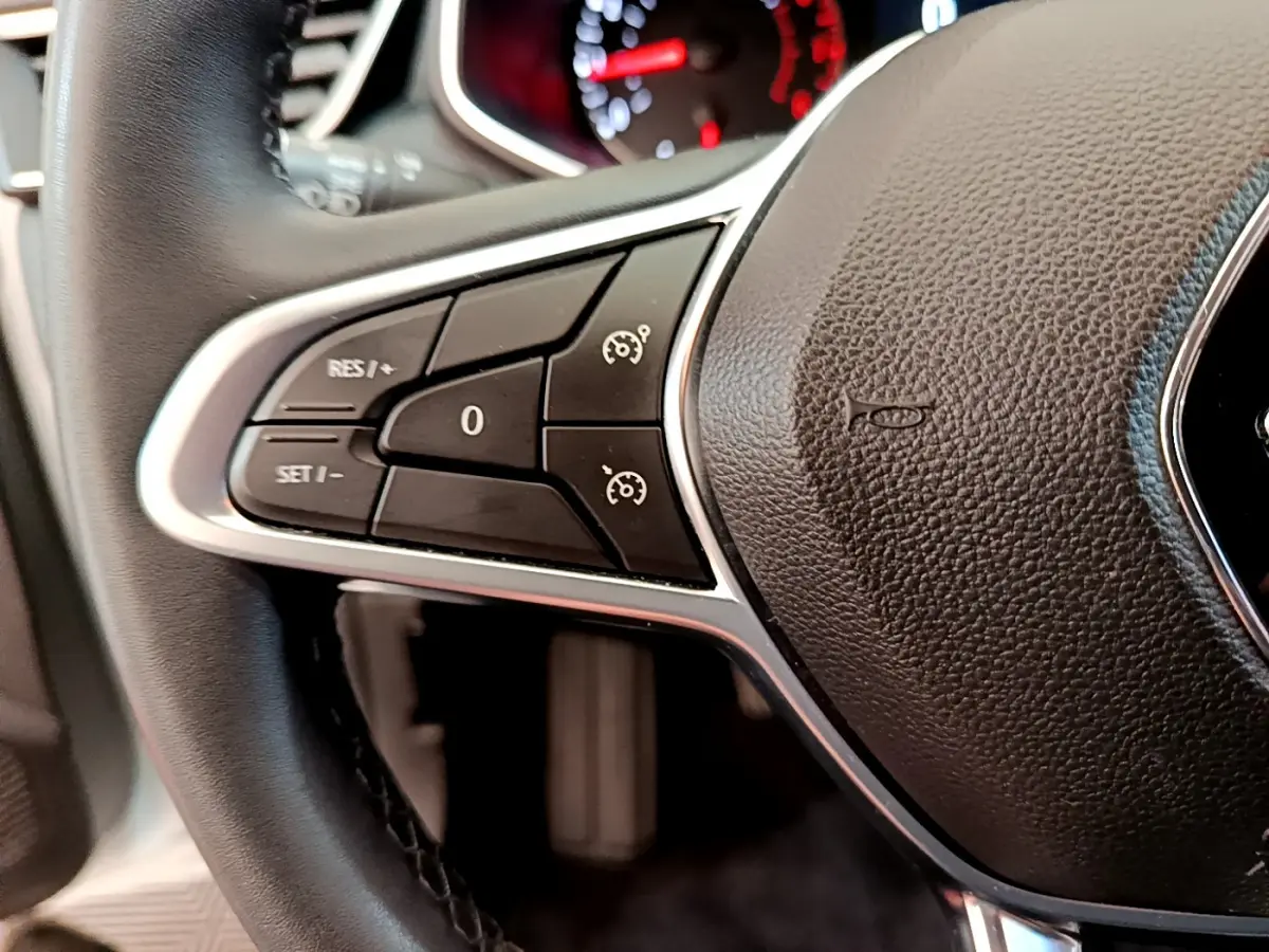 Gros plan sur le volant cuir synthétique de la Renault Clio Business blanc, avec commandes de régulateur de vitesse intégrées.