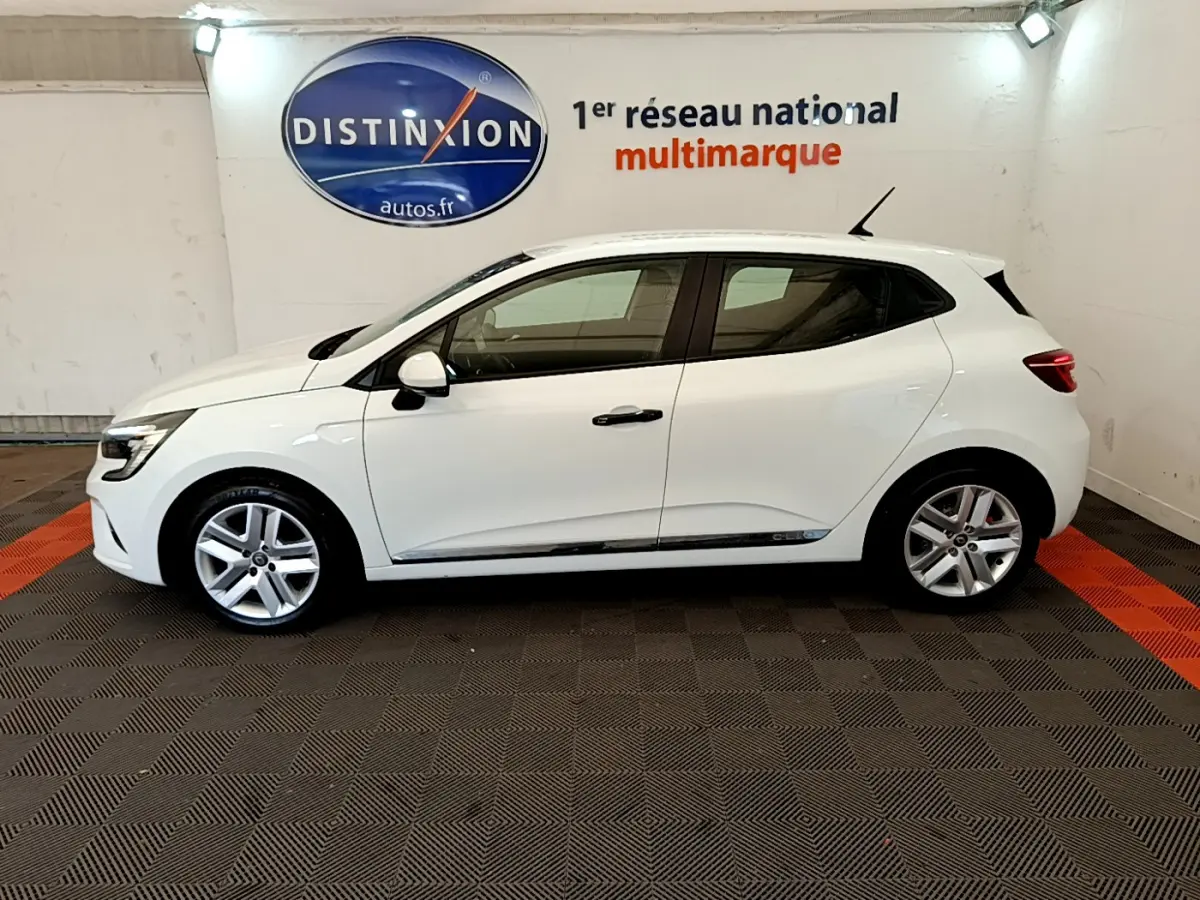 Profil côté gauche d'une Renault Clio Business blanche 2021, avec jantes alliage et vitres teintées, en intérieur showroom.