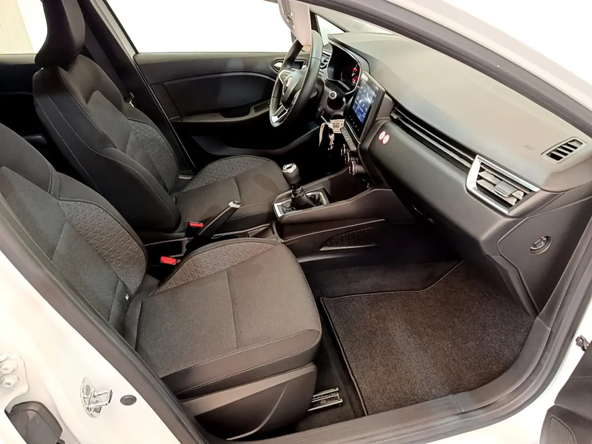 Intérieur côté passager de la Renault Clio Business blanche, montrant sièges noirs et tableau de bord moderne avec écran tactile.