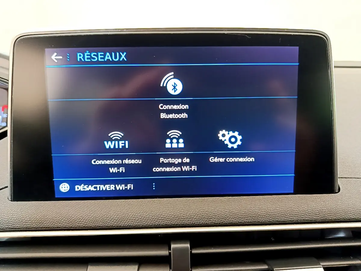 Écran tactile central affichant les options réseau Bluetooth et Wi-Fi dans l’habitacle d’un Peugeot 3008 gris foncé.