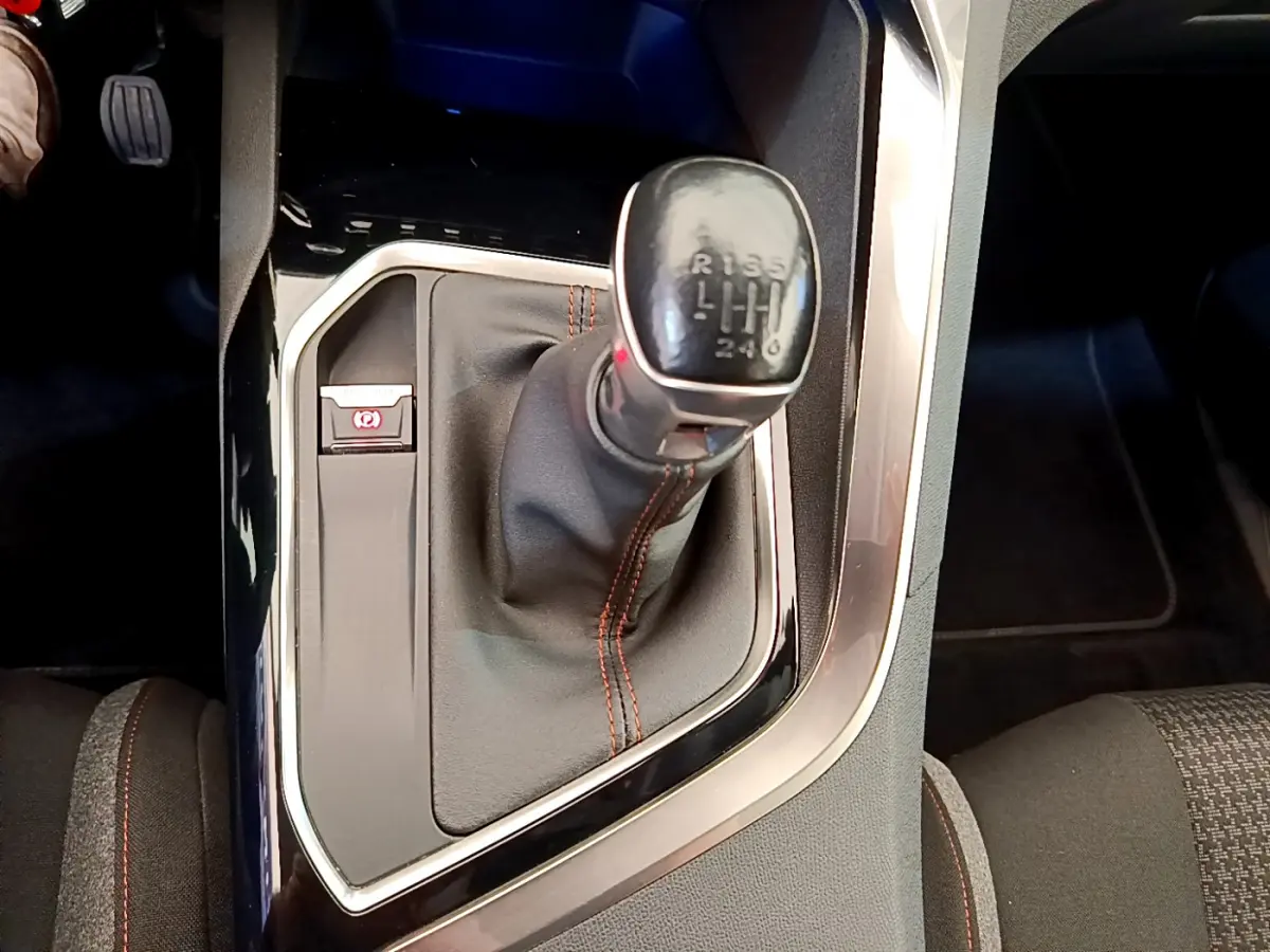 Vue rapprochée du levier de vitesse manuel noir avec coutures rouges dans une Peugeot 3008 gris foncé 2020.