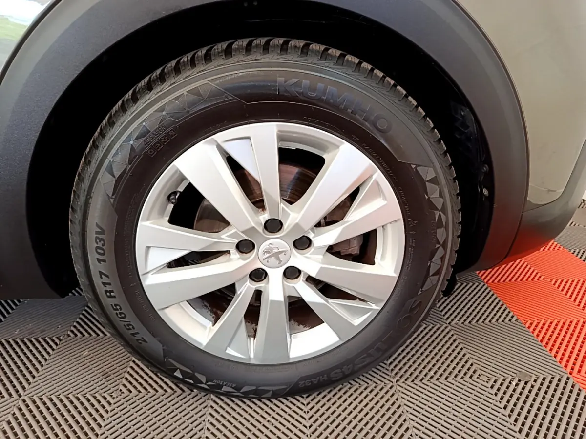 Gros plan sur la roue avant droite d’un Peugeot 3008 gris foncé, avec jante argentée et pneu Kumho.
