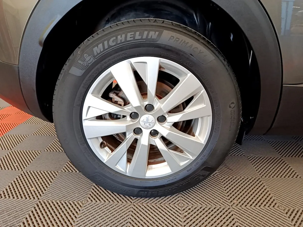 Gros plan sur la roue avant droite d’un Peugeot 3008 gris foncé, avec jante alliage et pneu Michelin Primacy 4.