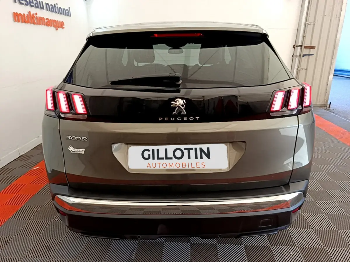 Vue arrière d'un Peugeot 3008 gris foncé avec feux arrière à LED allumés et bandeau noir brillant central.