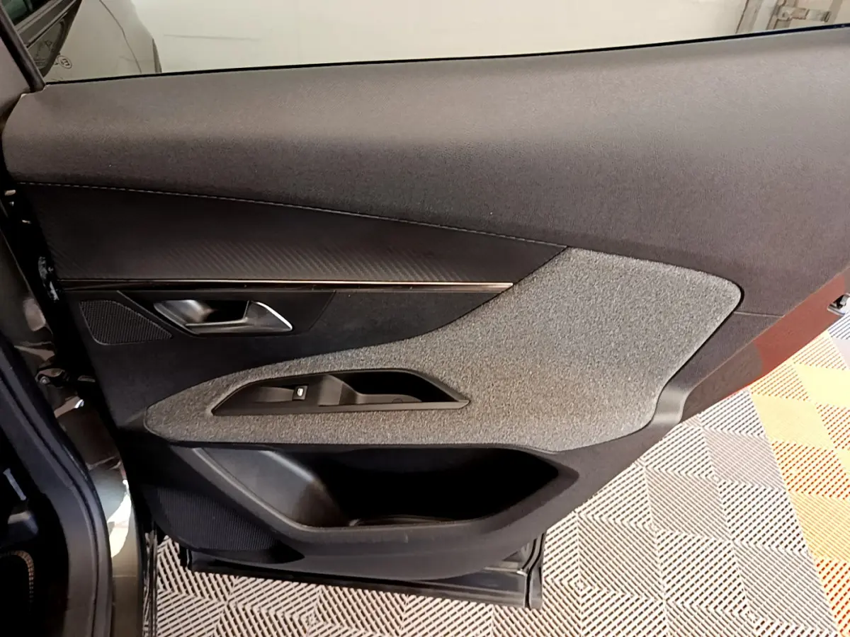 Vue rapprochée de la porte côté gauche du Peugeot 3008 gris foncé, avec insert tissu gris et commande de vitre.
