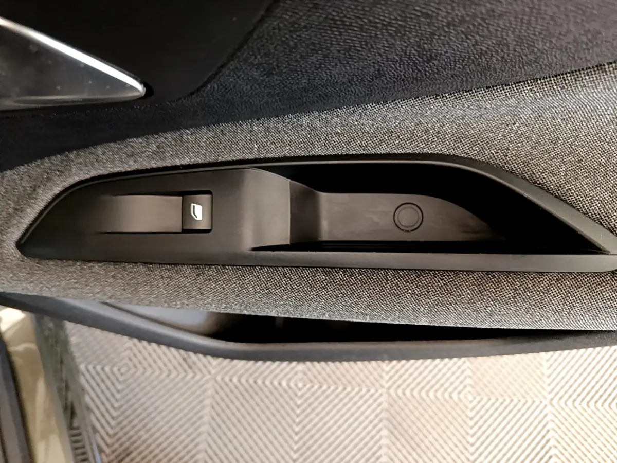 Détail de la commande de lève-vitre sur la porte côté conducteur du Peugeot 3008 gris foncé, intérieur tissu.