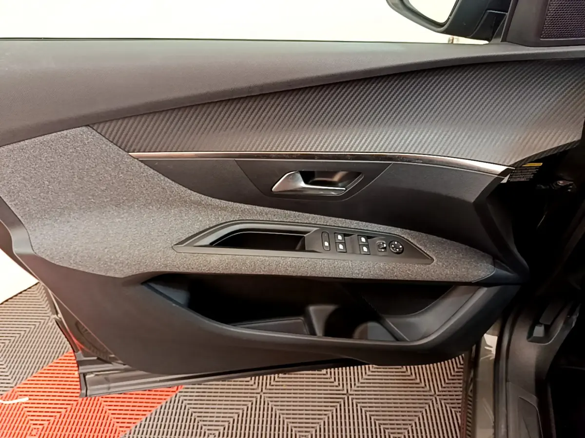 Vue intérieure côté gauche de la porte avant d’un Peugeot 3008 gris foncé avec commandes électriques et garniture texturée.