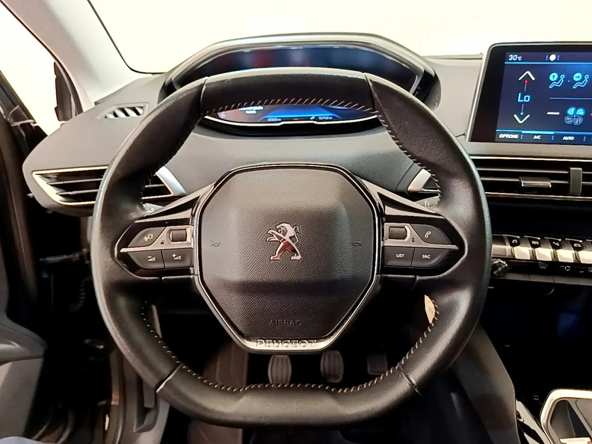 Vue intérieure centrée sur le volant cuir multifonctions d'une Peugeot 3008 2020, avec tableau de bord numérique et écran tactile.