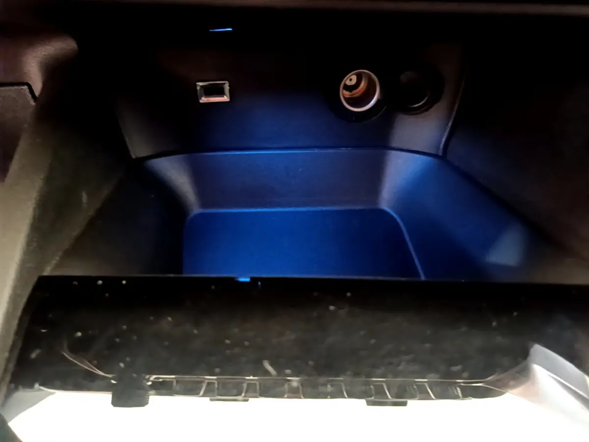 Gros plan sur le rangement réfrigéré noir de la Peugeot 3008 Puretech 130 S&S Active, éclairage bleu intérieur.