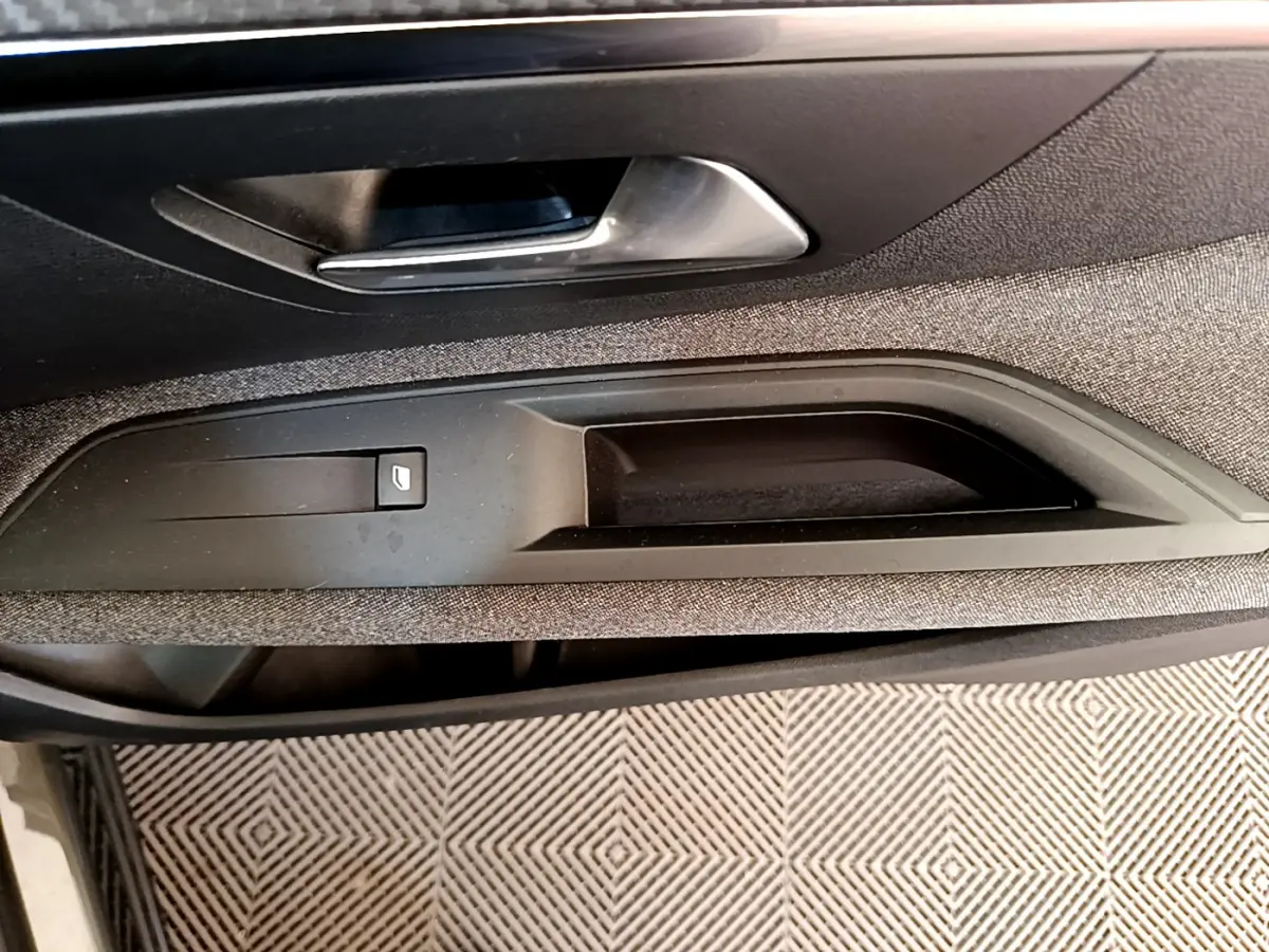 Détail de la poignée intérieure côté conducteur du Peugeot 3008 gris foncé, avec bouton de verrouillage des portes.