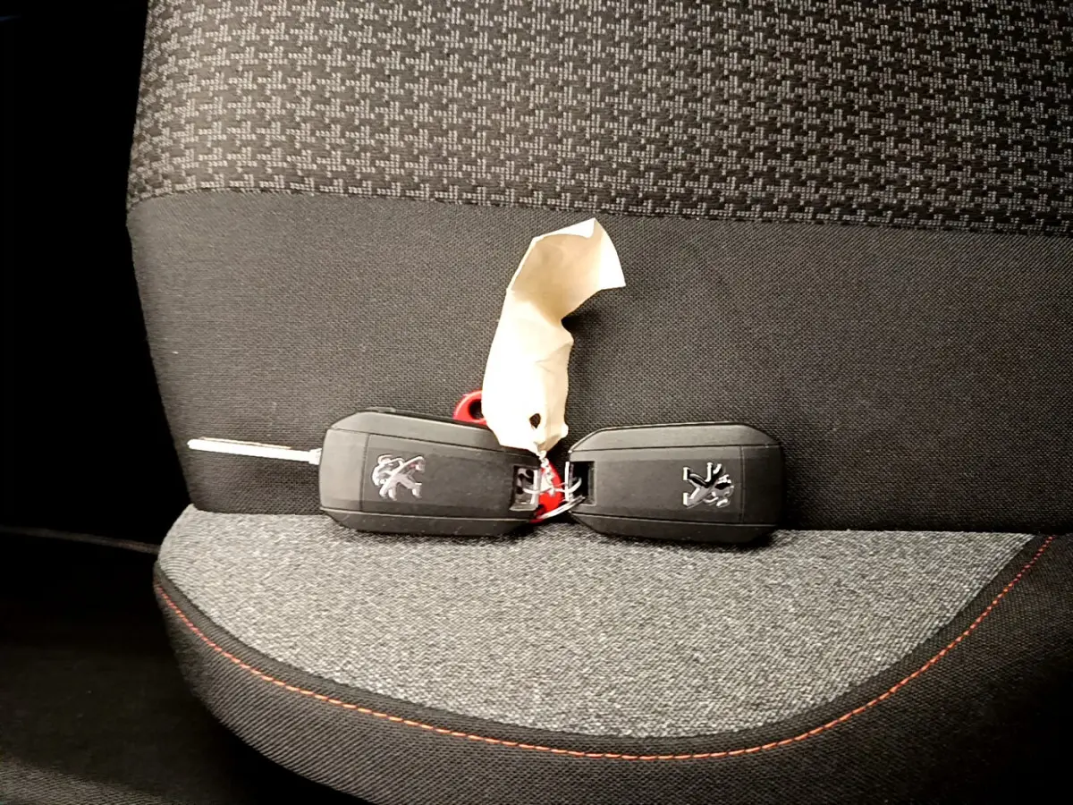 Gros plan sur deux clés Peugeot posées sur un siège tissu gris foncé avec surpiqûres rouges à l'intérieur d'un Peugeot 3008.