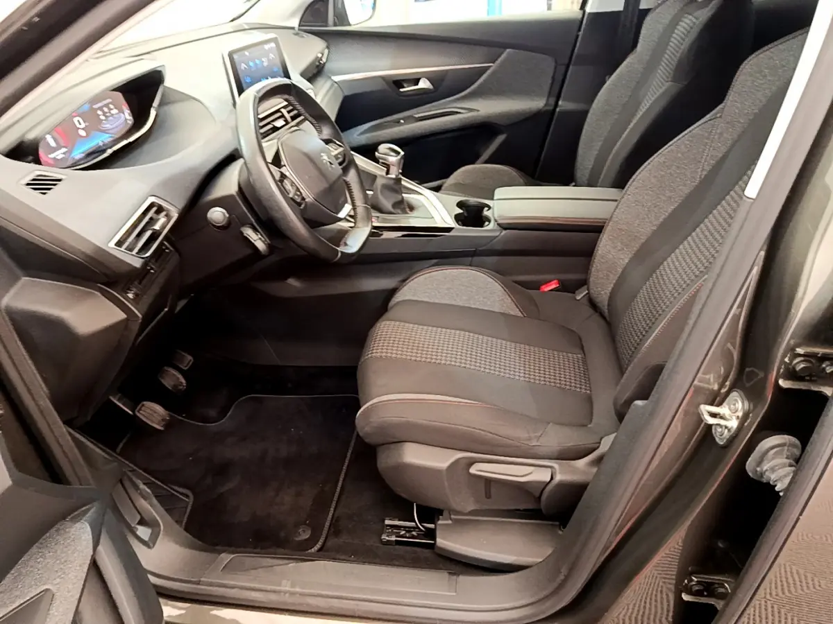 Intérieur avant droit du Peugeot 3008 gris foncé 2020, volant cuir, tableau de bord numérique et boîte manuelle.