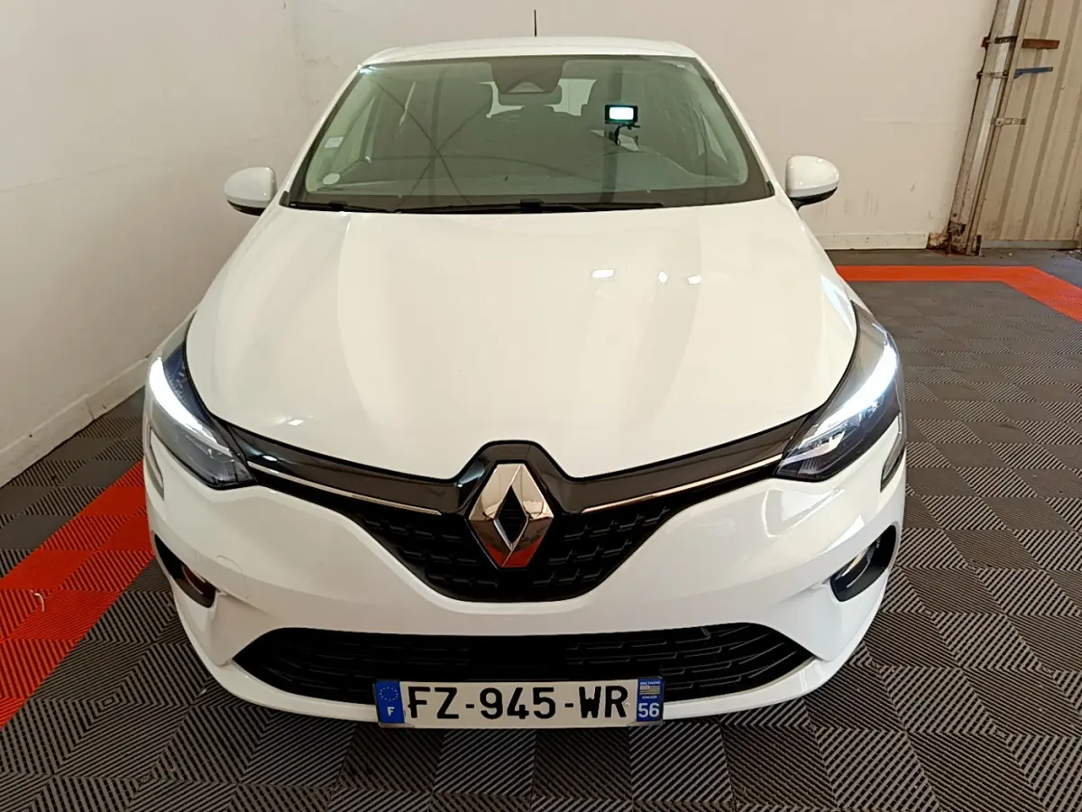 Vue de face d'une Renault Clio Business blanche avec phares LED allumés dans un garage.