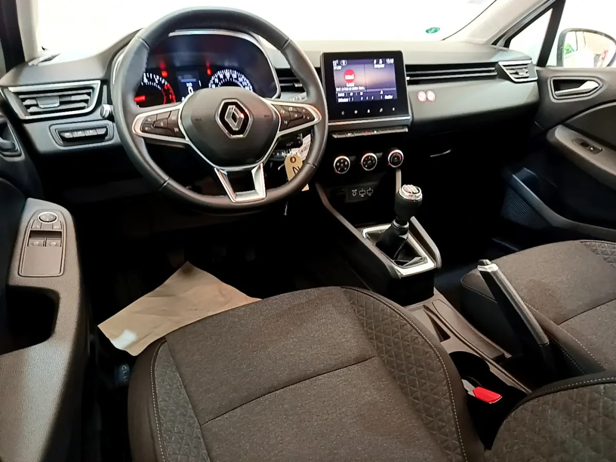 Intérieur avant de la Renault Clio Business blanc, vue côté conducteur sur volant cuir et écran tactile central.